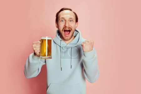 Photo for Portrait of young man, sport fan with excited happy look posing with lager foamy beer mug isolated over pink background. Win. Concept of emotions, taste, lifestyle, facial expression, Oktoberfest - Royalty Free Image