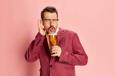 Photo for Portrait of stylish drunk man in a suit posing with glass of lager beer isolated on pink background. Good party. Hangover. Concept of emotions, taste, lifestyle, facial expression, Oktoberfest - Royalty Free Image