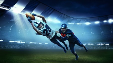 Téléchargez les photos : Des opposants. Deux joueurs de football américain actifs en mouvement, jouant, attrapant le ballon isolé au stade avec des lampes de poche. Concept de sport, défis, objectifs, force, compétition, équipe. - en image libre de droit