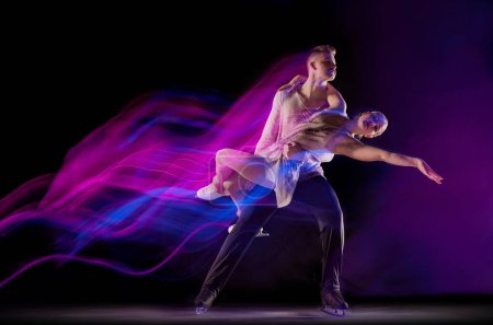 Photo for Portrait of young man and woman, figure skating athletes dancing isolated on black background in neon with mixed lights. Concept of movement, sport, beauty, hobby, competition, dance, choreography. Ad - Royalty Free Image