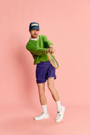 Photo for Portrait of young man in vintage sportive clothes playing tennis isolated over pink background. Students hobby. Concept of retro fashion, sport, 90s, lifestyle, youth, emotions. facial expression. Ad - Royalty Free Image