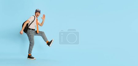 Téléchargez les photos : Portrait de jeune homme, étudiant en vêtements décontractés marchant joyeusement isolé sur fond bleu. Concept de jeunesse, mode de vie, éducation, émotions, expression faciale. Espace de copie pour la publicité - en image libre de droit