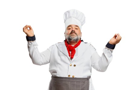 Téléchargez les photos : Portrait d'homme barbu, chef de restaurant en uniforme posant avec fière allure professionnelle isolé sur fond blanc. Concept de profession, profession, passe-temps, mode de vie, goût. Publicité - en image libre de droit