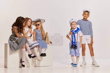 Photo for Portrait of children, boys and girls posing over grey background. Meeting, travelling, cruise fun . Concept of childhood, friendship, fun, lifestyle, fashion and retro style, emotions - Royalty Free Image