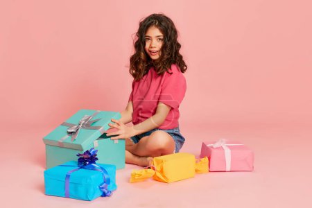 Photo for Portrait of beautiful young girl, teen, child posing with many present boxes over pink background. Birthday . Concept of celebration, party, womens day, emotions, holiday, happiness. Ad - Royalty Free Image