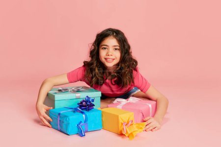 Photo for Portrait of beautiful young girl, teen, child posing with many present boxes over pink background. Excited kid. Concept of celebration, party, womens day, emotions, holiday, happiness. Ad - Royalty Free Image