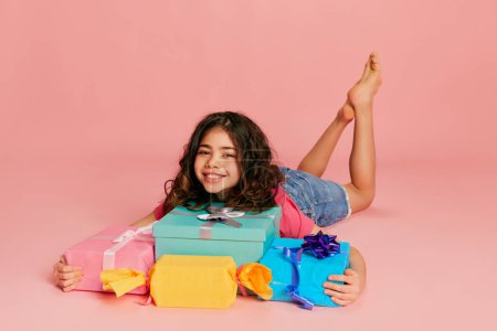 Photo for Portrait of beautiful young girl, teen, child posing with many present boxes over pink background. Happy kid. Concept of celebration, party, womens day, emotions, holiday, happiness. Ad - Royalty Free Image