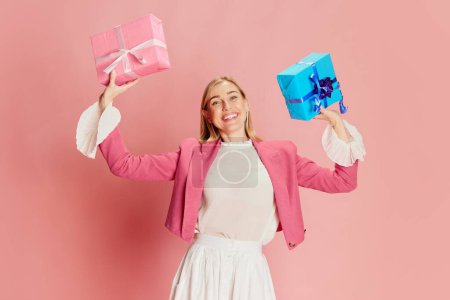 Photo for Delightful. Portrait of beautiful, stylish woman emotionally posing with present boxes over pink background. Concept of celebration, party, womens day, emotions, holiday, birthday, happiness. Ad - Royalty Free Image