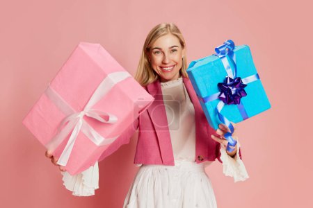 Photo for Portrait of beautiful, stylish woman emotionally posing with present boxes over pink background. Merry holidays. Concept of celebration, party, womens day, emotions, holiday, birthday, happiness. Ad - Royalty Free Image