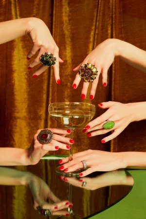 Téléchargez les photos : Mains féminines autour du verre avec champagne sur fond doré. Luxe, esthétique festive. Fête de Noël. Concept de vacances, fête, boisson. Couleurs complémentaires. Espace de copie pour l'annonce. Pop art - en image libre de droit