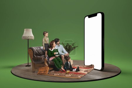 Téléchargez les photos : Jeune famille, homme, femme et enfants assis et regardant un énorme modèle 3D d'écran de téléphone. Concept de famille, achats en ligne, application, ventes, information, style rétro. Publicité. - en image libre de droit