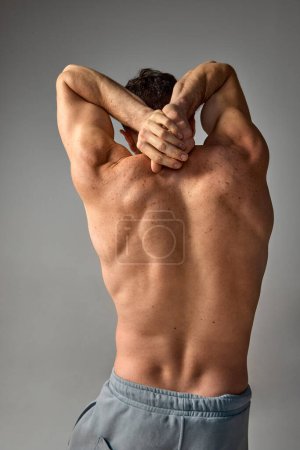 Photo for Rear view of relief, muscular male body. Freckled, strong shoulders. Man posing shirtless over grey studio background. Concept of mens health and beauty, body and skin care, fitness. Body art - Royalty Free Image