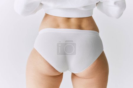 Téléchargez les photos : Cropped image of female body, buttocks in underwear posing over grey studio background. Back view. Anti cellulite care. Concept of body and skin care, fitness, natural beauty, health, wellness. - en image libre de droit