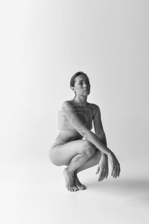 Téléchargez les photos : Black and white photography. Tender woman sitting, posing in underwear. Self-care, femininity, acceptance. Concept of body and skin care, fitness, natural beauty, health, wellness. - en image libre de droit