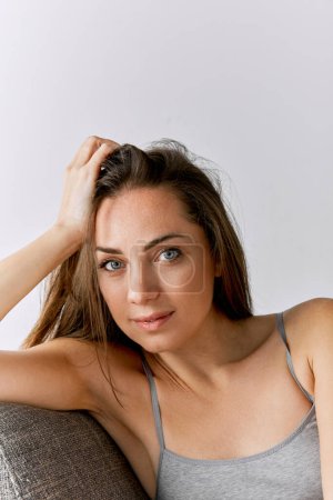 Téléchargez les photos : Portrait of beautiful woman with well-kept natural skin posing over grey studio background. Femininity. Concept of body and skin care, fitness, natural beauty, health, wellness. - en image libre de droit