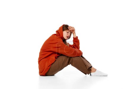 Photo for Portrait of teen girl sitting on floor over white background. Suffering from breakdown, stress, depression and loneliness. Concept of psychology, inner world, mental health, emotions, feelings - Royalty Free Image