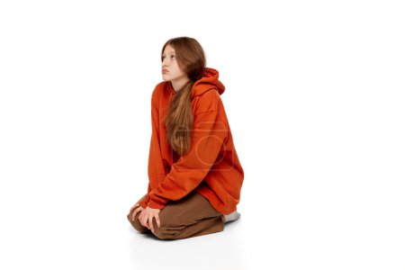 Photo for Portrait of teen girl sitting on floor with bored over white background. Isolation. Introvert lifestyle. Concept of psychology, inner world, mental health, emotions, feelings, youth - Royalty Free Image