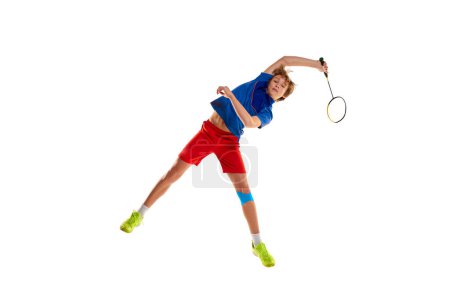 Téléchargez les photos : Portrait of teen boy in uniform playing badminton, training isolated over white background. In a jump, serving. Concept of sportive lifestyle, motion, action, competition, motivation, hobby - en image libre de droit