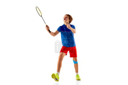 Foto de Portrait of teen boy in uniform, badminton player during game, training isolated over white background. Winning emotions. Concept of sportive lifestyle, motion, action, competition - Imagen libre de derechos
