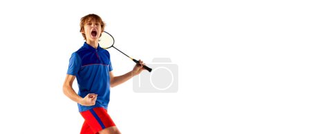 Foto de Portrait of teen boy in uniform, badminton player after successful game isolated over white background. Winning emotions. Banner. Concept of sportive lifestyle, motion, action, competition - Imagen libre de derechos