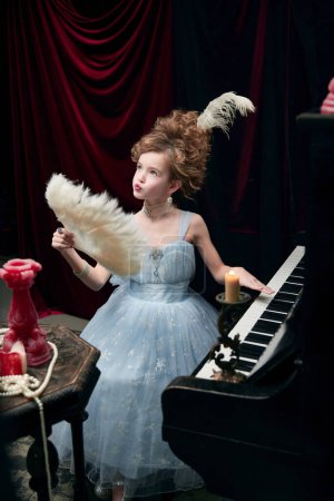 Photo for Portrait of cute little girl, child in image of medieval royal person posing in fabulous dress with feather fan. Concept of historical remake, comparison of eras, medieval fashion, emotions, childhood - Royalty Free Image