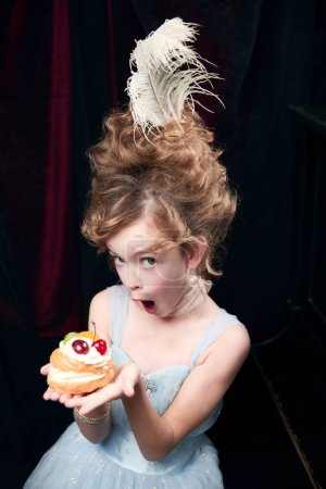 Téléchargez les photos : Portrait of cute little girl, child in image of medieval royal person emotionally looking on cake. Birthday. Concept of historical remake, comparison of eras, medieval fashion, emotions, childhood - en image libre de droit