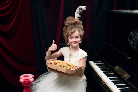 Photo for Portrait of cute little girl, child in image of medieval royal person sitting at the piano with pizza. Delicious taste. Concept of historical remake, comparison of eras, medieval fashion, childhood - Royalty Free Image