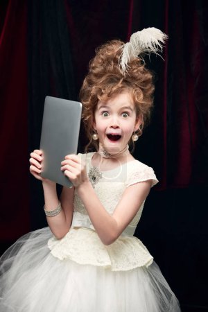 Photo for Portrait of cute little girl, child in image of medieval royal person emotionally posing with tablet. Concept of historical remake, comparison of eras, medieval fashion, emotions, childhood - Royalty Free Image