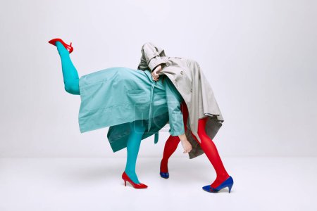 Foto de Portrait of two young girls in bright red and blue tights and coat posing over grey studio background. Self-expression. Concept of modern fashion, queer, art photography, weird people, creativity - Imagen libre de derechos