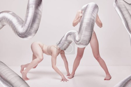 Téléchargez les photos : Surreal vision. Creative photography with two young girls posing in nude underwear over beige studio background. Concept of cringe, queer, art photography, weird people, creativity - en image libre de droit