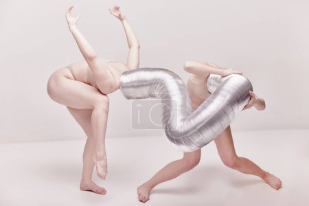 Téléchargez les photos : Self-expression. Creative photography with two young girls posing in nude underwear over beige studio background. Concept of cringe, queer, art photography, weird people, creativity - en image libre de droit