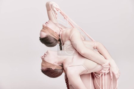 Foto de Beauty. Portrait of two young girls posing in underwear and ropes with eyes closed over light studio background. Concept of modern fashion, queer, art photography, weird people, creativity - Imagen libre de derechos