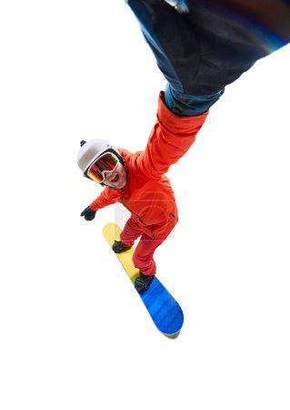 Téléchargez les photos : Selfie in motion. Portrait of active man, snowboarder in uniform riding on snowboard isolated over white studio background. Concept of winter sport, action, motion, hobby, leisure time - en image libre de droit