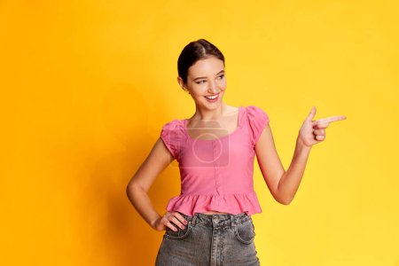 Photo for Spreading positivity. Portrait of young beautiful girl posing in pink blouse over yellow studio background. Concept of youth, beauty, fashion, lifestyle, emotions, facial expression. Ad - Royalty Free Image
