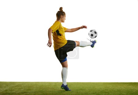 Téléchargez les photos : Young woman, professional female football player in motion, training, playing football, soccer isolated over white background. Concept of sport, action, motion, goals, competition, hobby, ad. - en image libre de droit