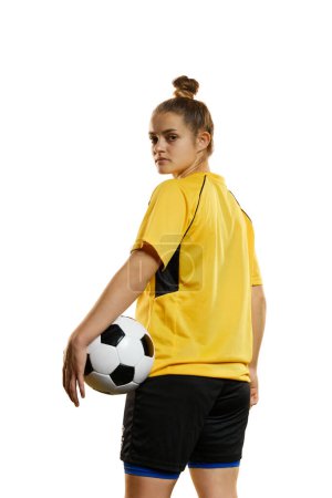 Foto de Young woman, professional female football, soccer player in yellow uniform posing with ball isolated over white studio background. Concept of sport, action, motion, goals, competition, hobby, ad. - Imagen libre de derechos