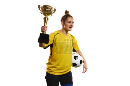 Foto de Young woman, professional female football, soccer player in yellow uniform posing with trophy and ball isolated over white studio background. Concept of sport, goals, competition, hobby, ad. - Imagen libre de derechos
