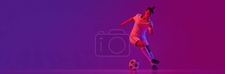Foto de Young professional female football, soccer player in motion, training over gradient pink background in neon. Dribbling. Banner, flyer. Concept of sport, action, motion, goals, competition, hobby, ad. - Imagen libre de derechos