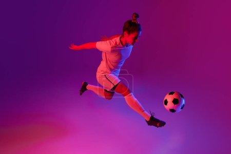 Photo for Dribbling. Young professional female football, soccer player in motion, training, playing over gradient pink background in neon light. Concept of sport, action, motion, goals, competition, hobby, ad. - Royalty Free Image