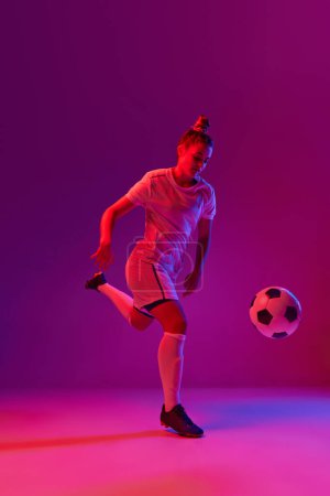 Photo for Winner. Young professional female football, soccer player in motion, training, playing over gradient pink background in neon light. Concept of sport, action, motion, goals, competition, hobby, ad. - Royalty Free Image