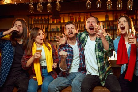 Photo for Emotional young people, friends meeting at pub to watch online game translation and drink beer. Emotions of happiness. Winning game. Competition, championship, match translation. Emotions. - Royalty Free Image