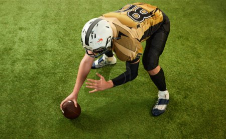 Téléchargez les photos : Top view. Man, american football player in motion, training, starting game over sports field grass background. Concept of sport, movement, achievements, competition, hobby, game - en image libre de droit
