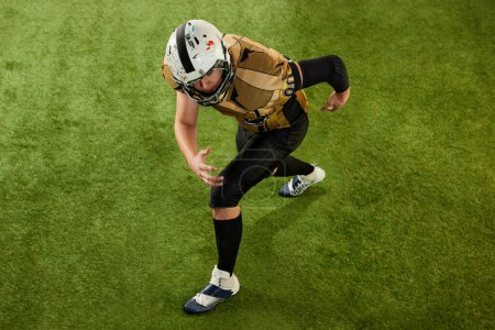Téléchargez les photos : Top view. Man, american football player in motion, training, preparing before game over sports field grass background. Concept of sport, movement, achievements, competition, hobby - en image libre de droit