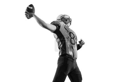 Téléchargez les photos : Black and white photo of proud man, american football player in motion, training over white studio background. Concept of sport, movement, achievements, competition, hobby. Copy space for ad - en image libre de droit