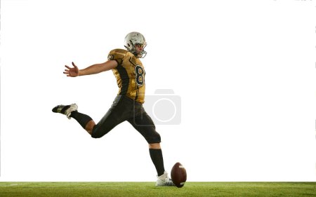 Téléchargez les photos : Kicking ball with leg. Man, american football player in uniform, in motion, training over white studio background. Concept of sport, movement, achievements, competition, hobby. Copy space for ad - en image libre de droit