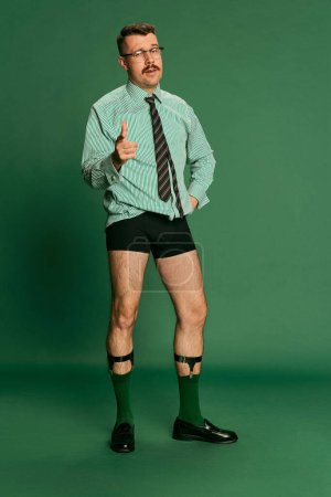 Photo for Boss. Portrait of handsome man, businessman in shirt without pants, in underwear posing over green studio background. Concept of emotions, business, occupation, facial expression, fashion - Royalty Free Image