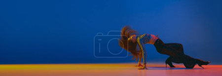 Foto de Portrait of young girl dancing heels dance in stylish clothes over blue background in neon light. Banner, flyer. Concept of dance lifestyle, modern style, contemporary, youth culture, self-expression - Imagen libre de derechos