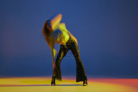 Foto de Portrait of young girl dancing heels dance in stylish clothes on blue background in neon light with mixed lights. Concept of dance lifestyle, modern style, contemporary, youth culture, self-expression - Imagen libre de derechos