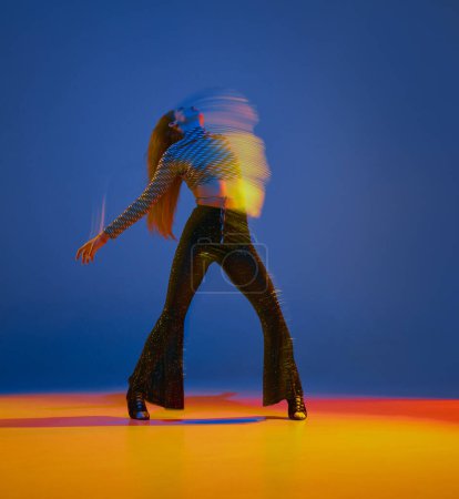 Téléchargez les photos : Portrait of young girl dancing heels dance in stylish clothes over blue background in neon with mixed lights. Concept of dance lifestyle, modern style, contemporary, youth culture, self-expression - en image libre de droit