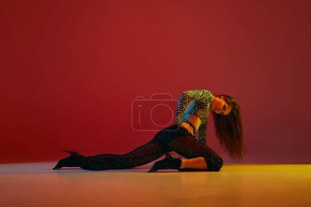Photo for Portrait of young girl dancing heels dance in stylish clothes over red background in neon light. Concept of dance lifestyle, modern style, contemporary dance, youth culture, self-expression - Royalty Free Image